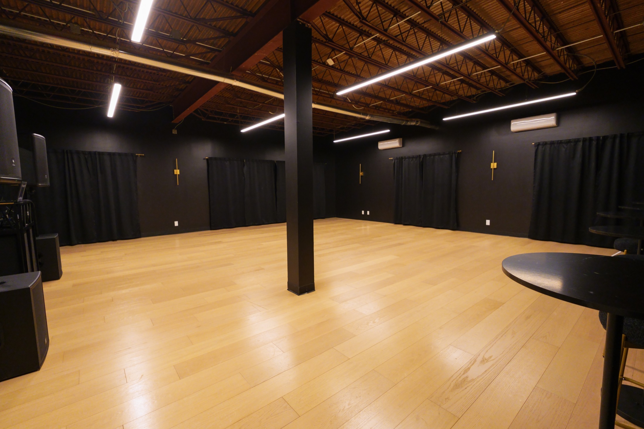 Cato's spacious main room with warm wood floors, dark walls and exposed ceiling